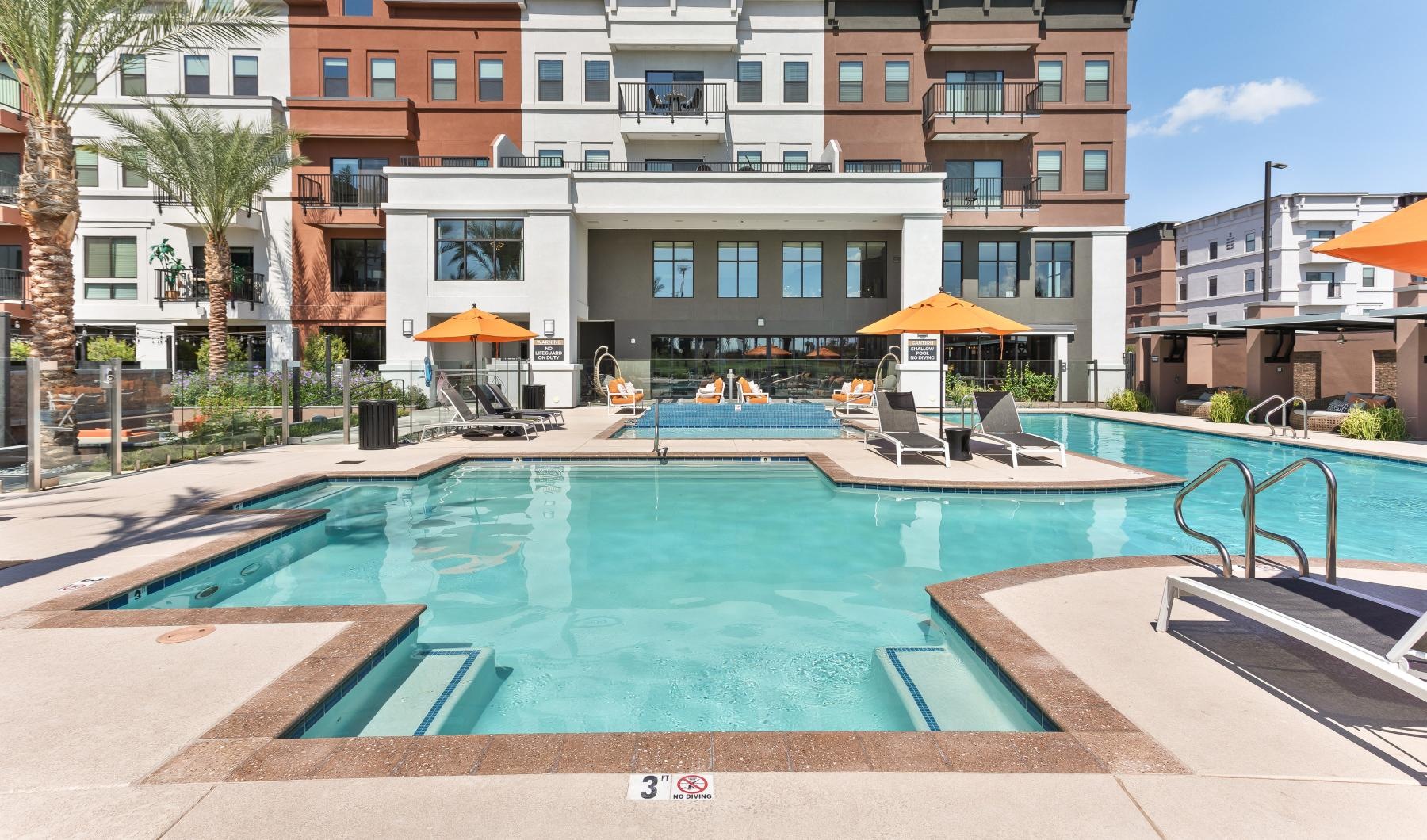 Shimmering resort-style pool Swimming pool and lounge pool surrounded by lounge chairs in front of the Summit at San Marcos apartment complex in Chandler, AZ