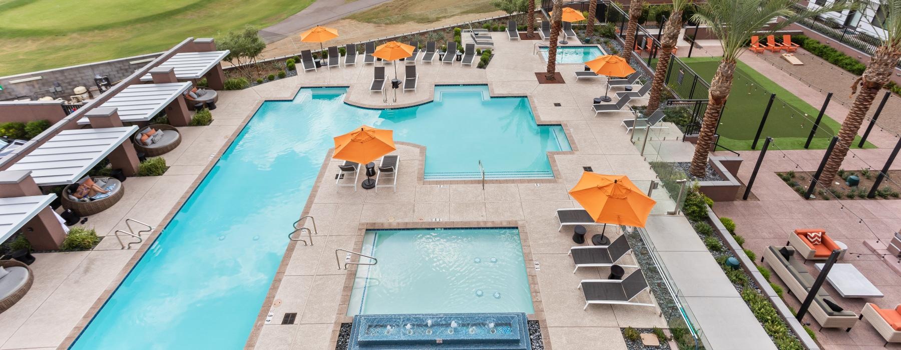 a pool with a lounge chair and umbrellas by a building